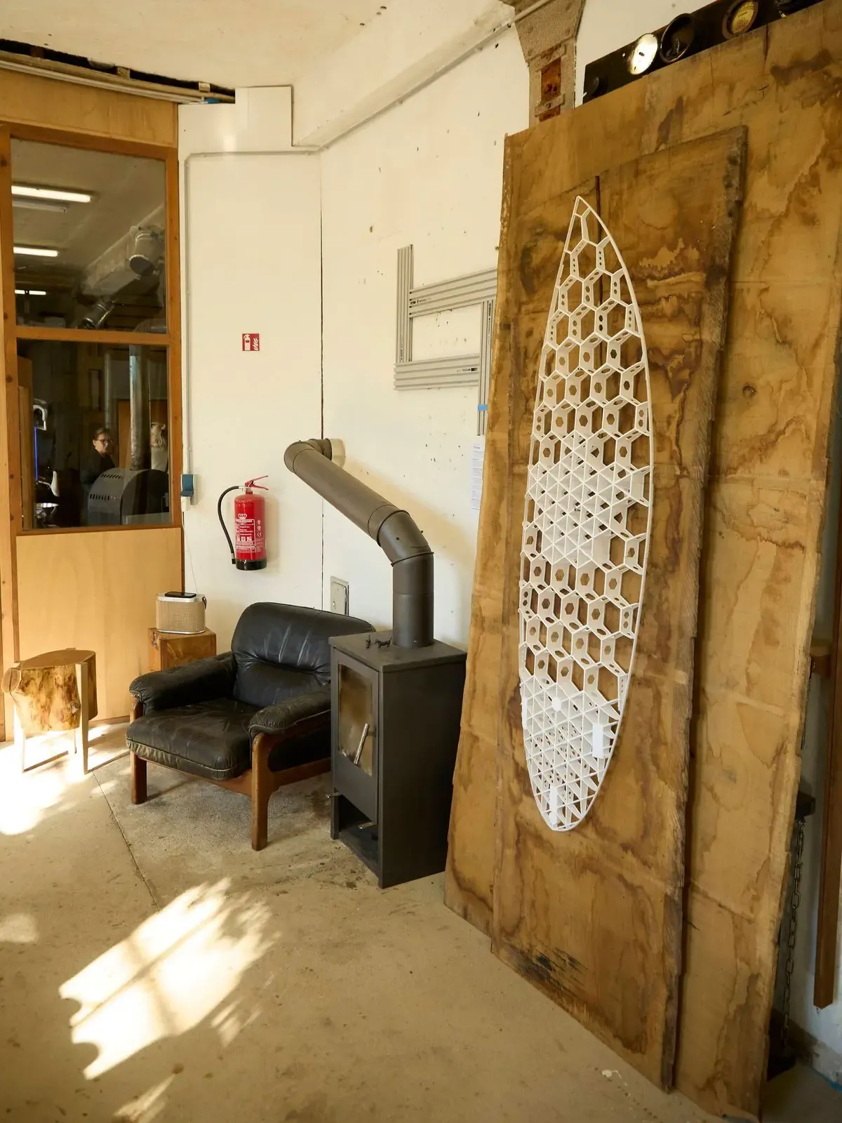 Werkstattecke mit Ofen und Sessel, rechts der gedruckte Wabenkern an der Wand