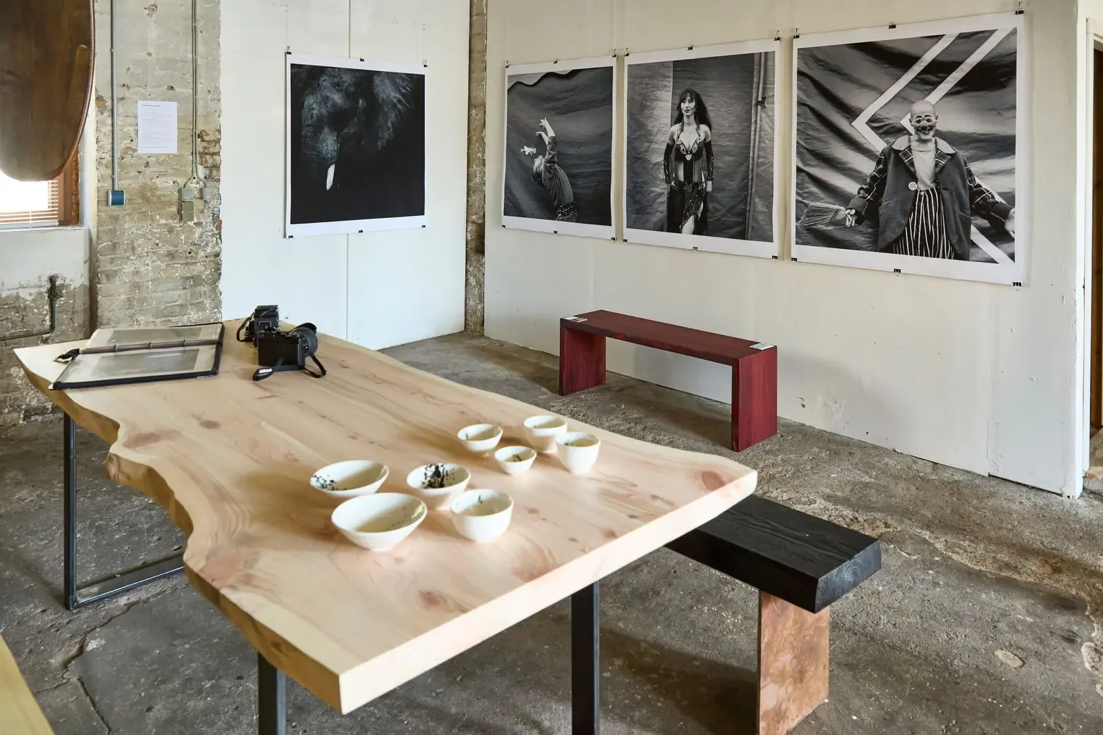 Tisch und Bänke aus Holz von Ingo Martens mit Keramik von Anja Kühn, an der Wand Fotografien von Arendt Schmolze