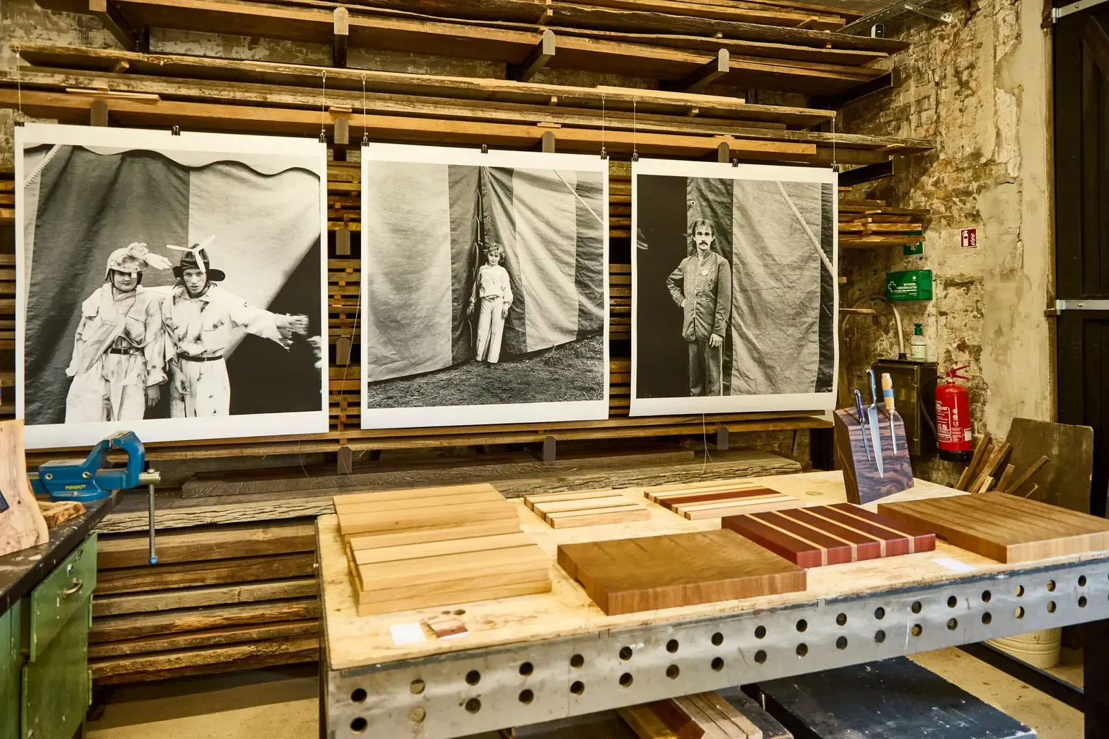 Holzbrettchen von Ingo Martens auf der Werkbank, dahinter Fotografien von Arendt Schmolze