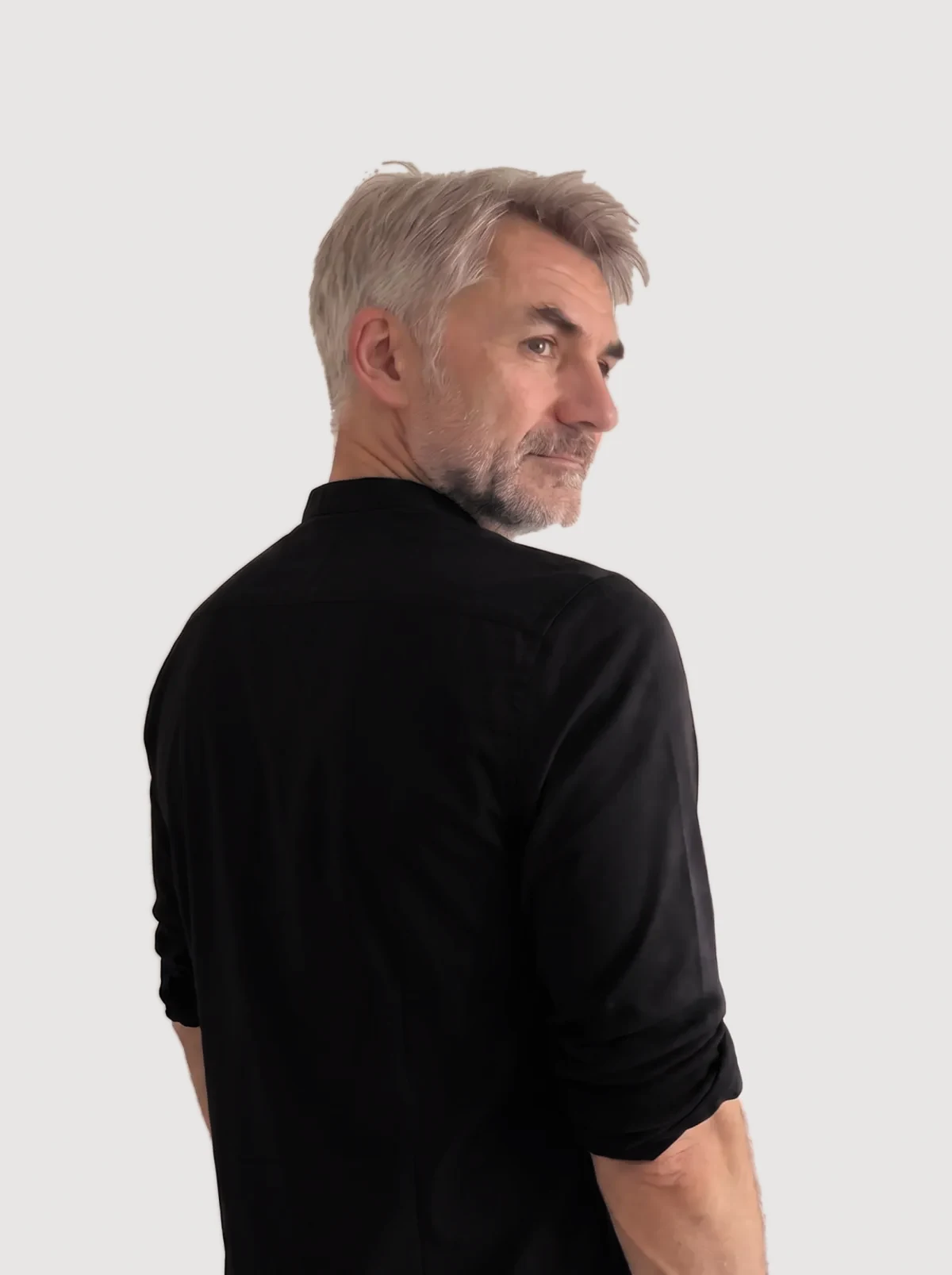 Tobias Herold im schwarzen Hemd, blickt über die Schulter