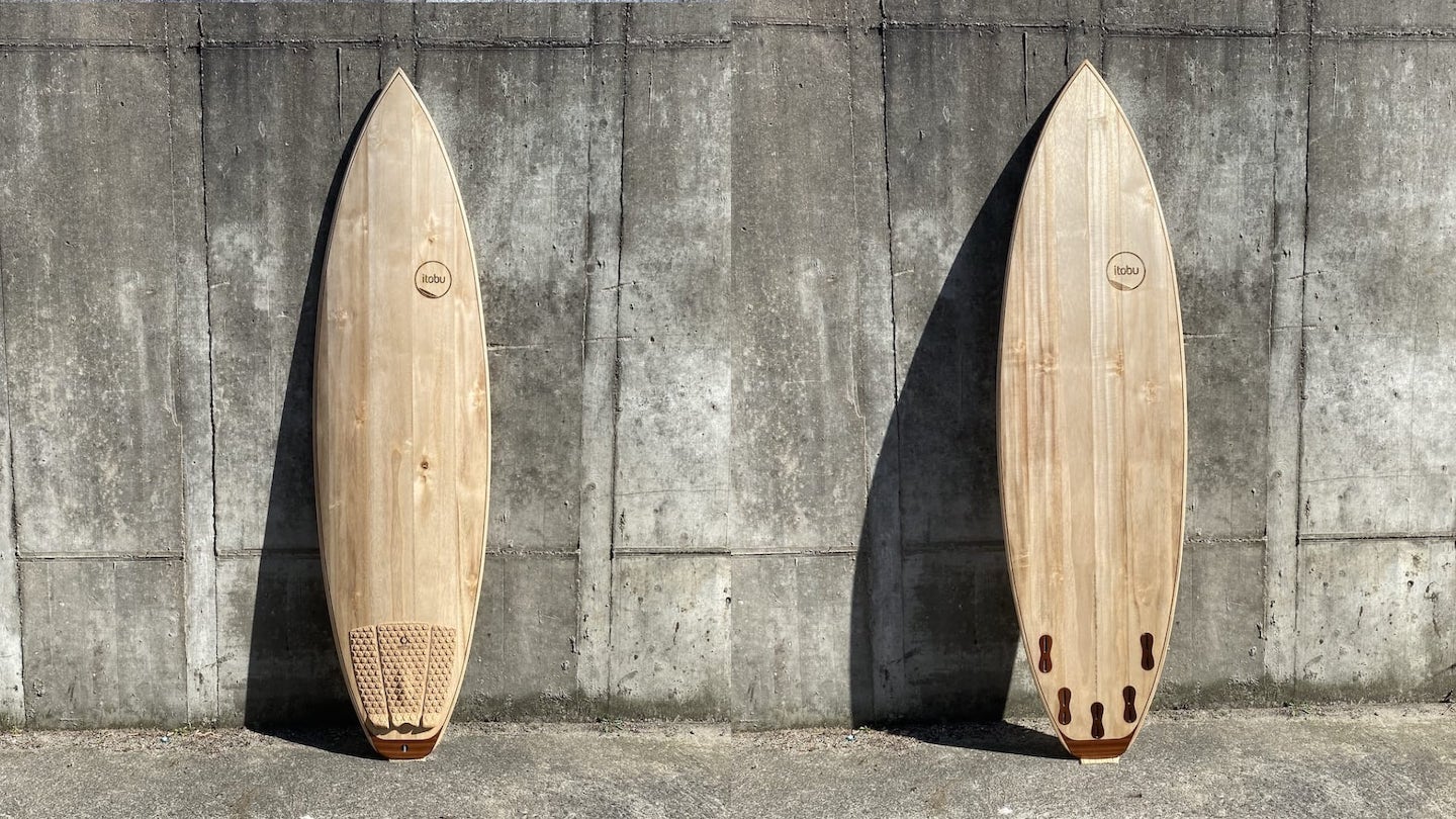 Holz-Surfboard in Vorder- und Rückansicht vor Betonmauer